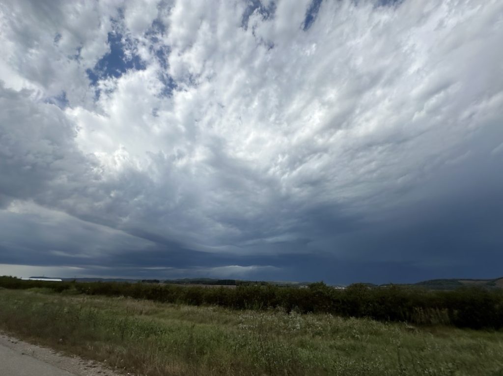 A photo of thunderstorm clouds on the horizon of a farm field.